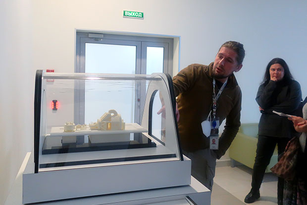 Михаил Черкашин демонстрирует макет протонной установки в холле протонного центра  МИБС