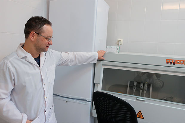 Доктор показывает аппарат в молекулярно-генетической лаборатории